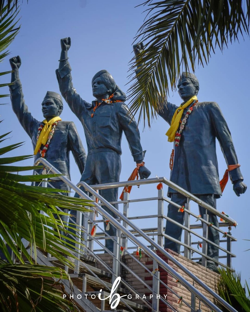 Jagraon Bridge, Ludhiana, with its freedom fighter statues of Bhagat Singh, Rajguru, and Sukhdev, framed by palm fronds against a blue sky.