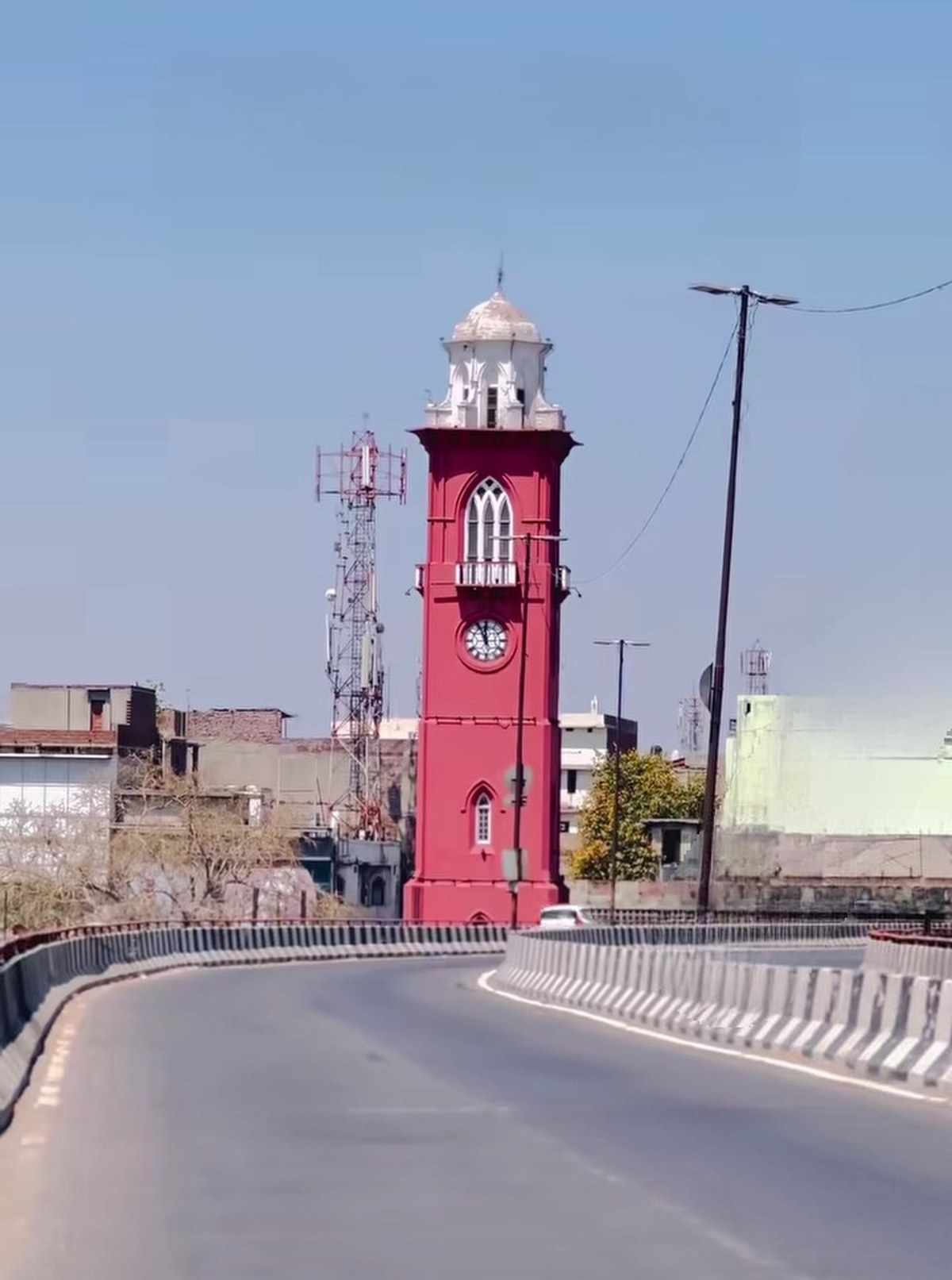 The red-and-white Ghanta Ghar clock tower in Ludhiana, Punjab, rising against a clear blue sky.
