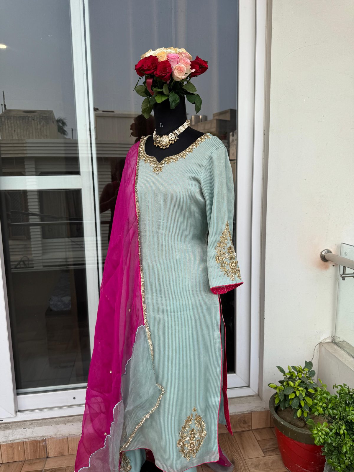 Front view of a mint-green suit with a gold beaded V-neckline and gold floral cuff embroidery, paired with a hot-pink organza dupatta.